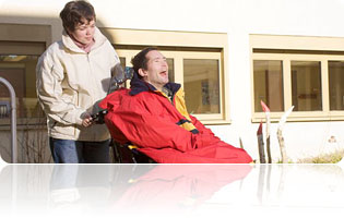 Ehrenamtliche Tätigkeit im Sankt-Josefshaus: Eine Frau geht mit einen Mann im Rollstuhl spazieren